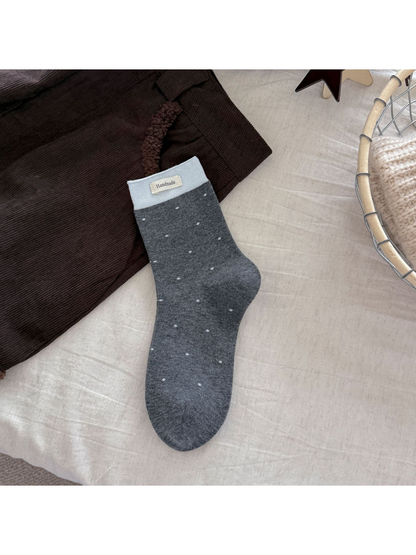 Dark gray polka-dot crew sock with a light gray ribbed cuff and rectangular label