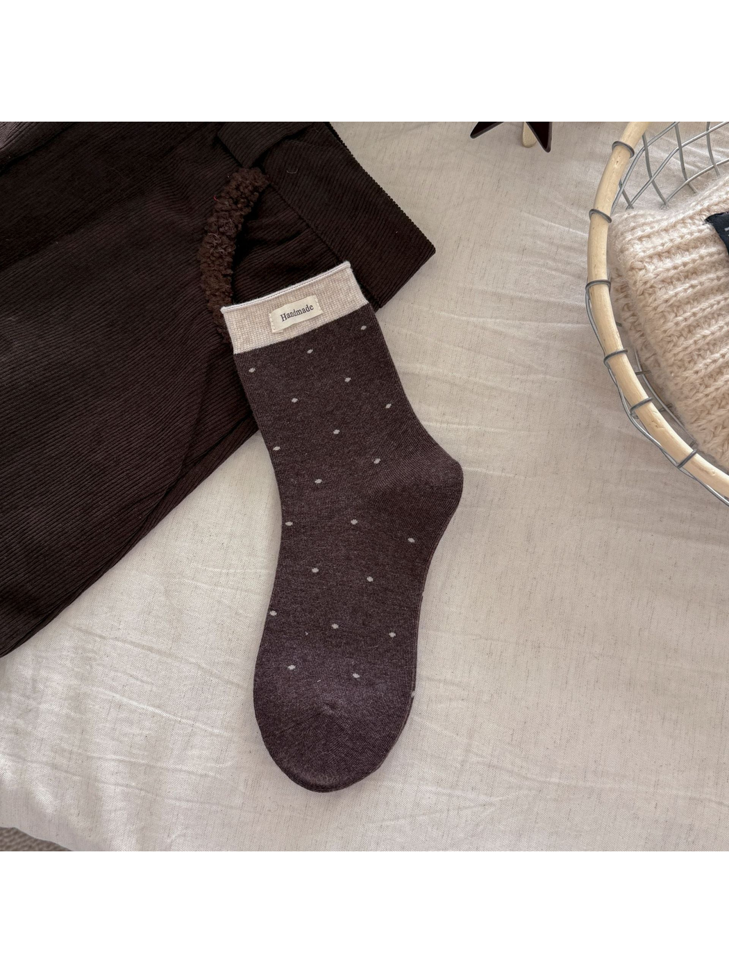 Dark brown polka-dot crew sock with a beige ribbed cuff and rectangular label
