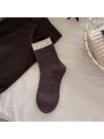 Dark brown polka-dot crew sock with a beige ribbed cuff and rectangular label