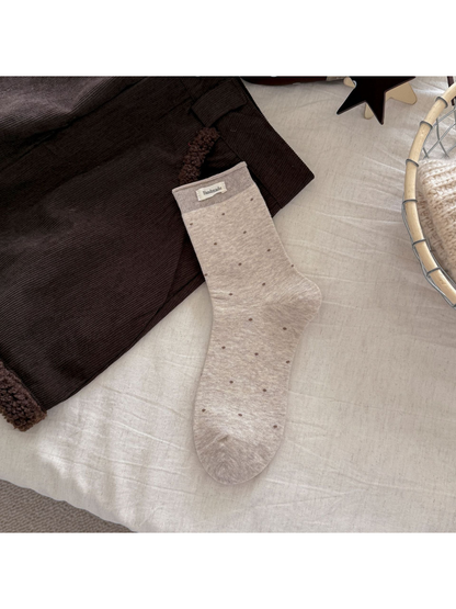 Beige polka-dot crew sock with a taupe ribbed cuff and rectangular label