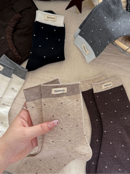Five polka-dot sock colors arranged together in a neutral flat lay