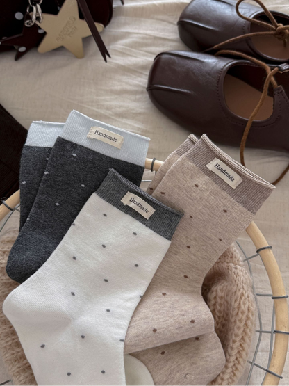 Dark gray, white and beige polka-dot crew socks displayed together