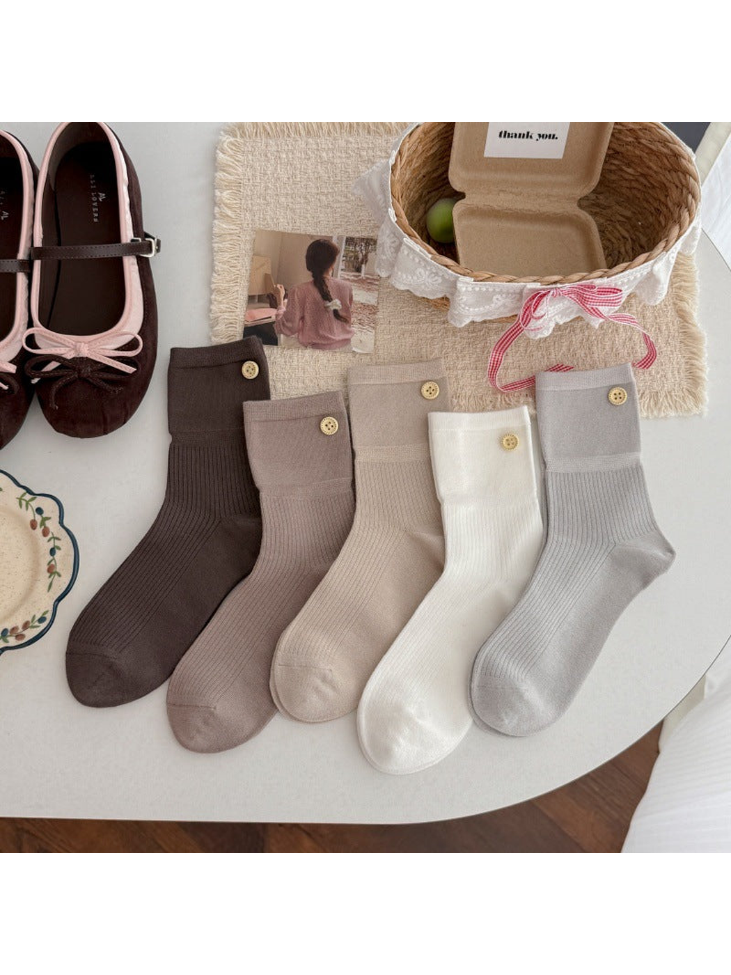 Five neutral-colored crew socks with ribbed legs and gold-tone button accents