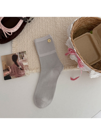 Light gray crew sock with a ribbed leg and gold-tone button accent, flat lay