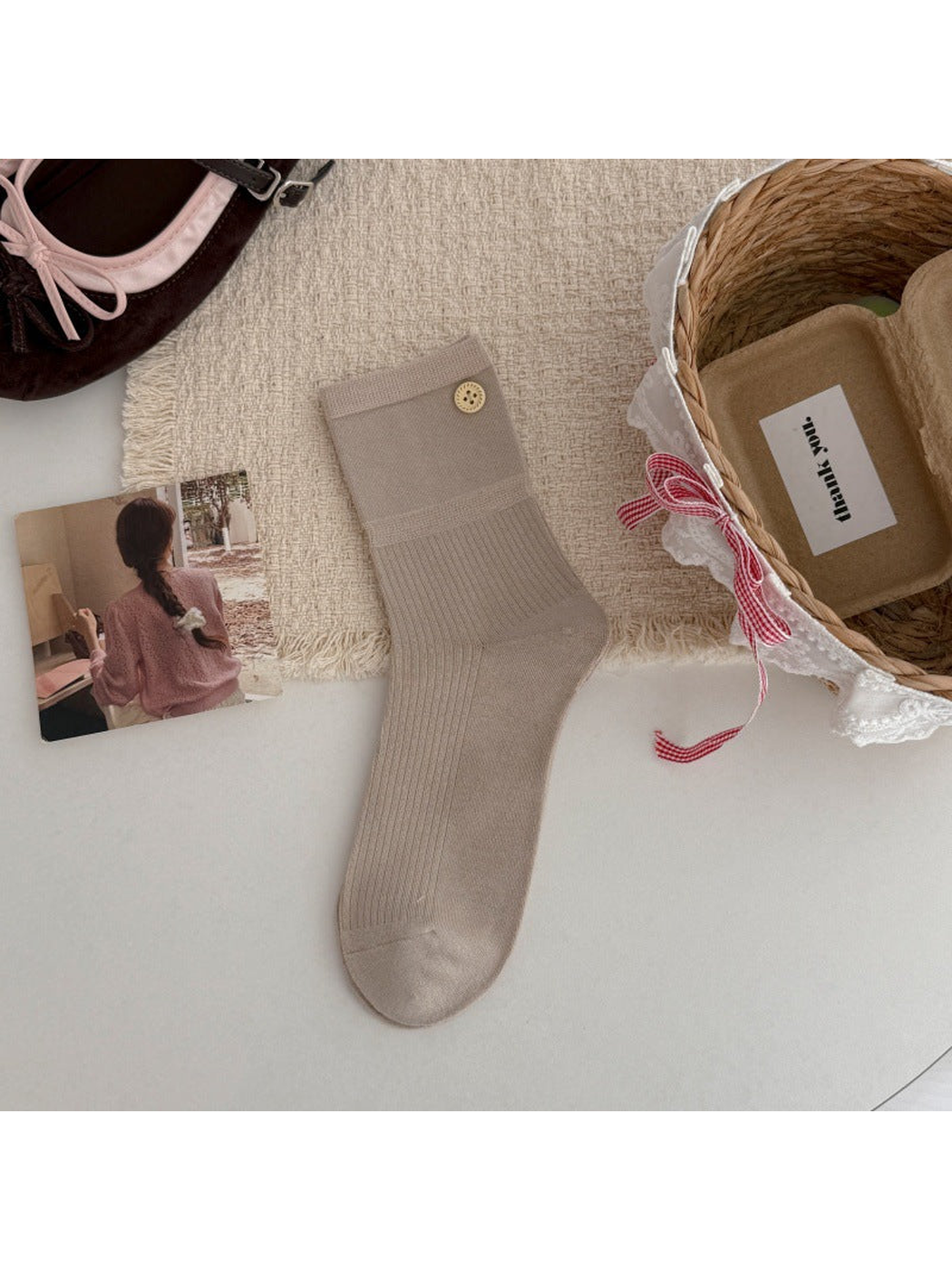 Beige crew sock with a ribbed leg and gold-tone button accent, flat lay