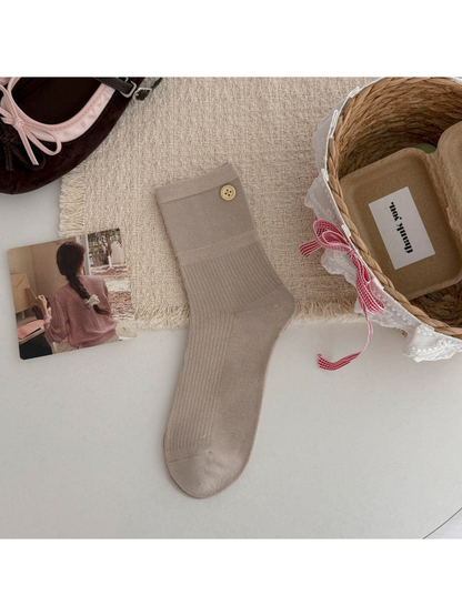 Beige crew sock with a ribbed leg and gold-tone button accent, flat lay