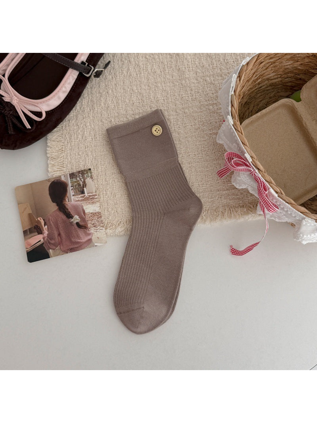 Taupe crew sock with a ribbed leg and gold-tone button accent, flat lay