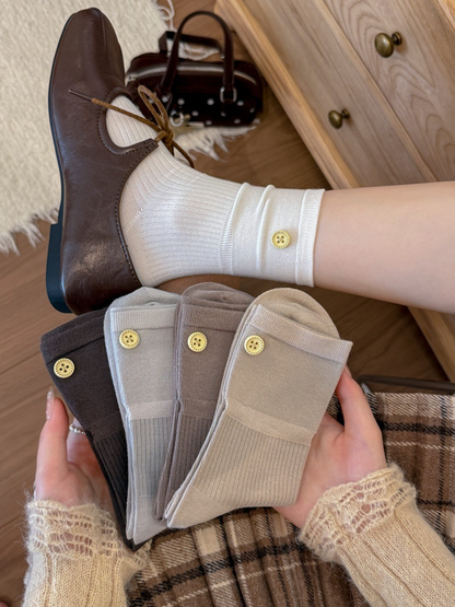 White crew sock worn with a brown lace-up shoe while four neutral color options are held