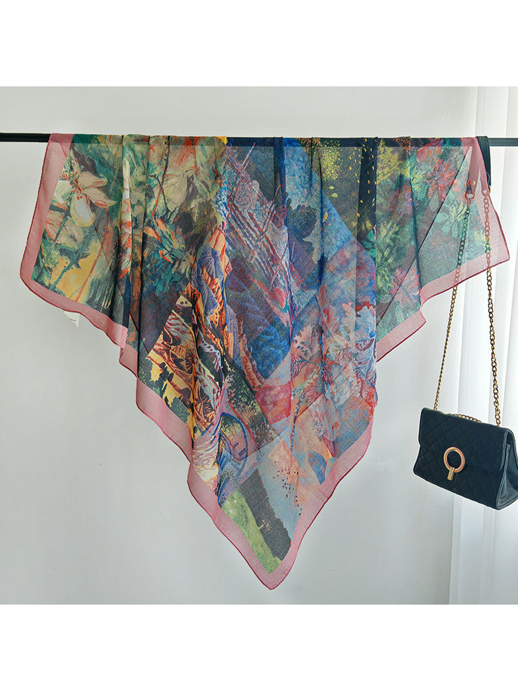 Multicolor square scarf spread across a rail to show its flowing drape