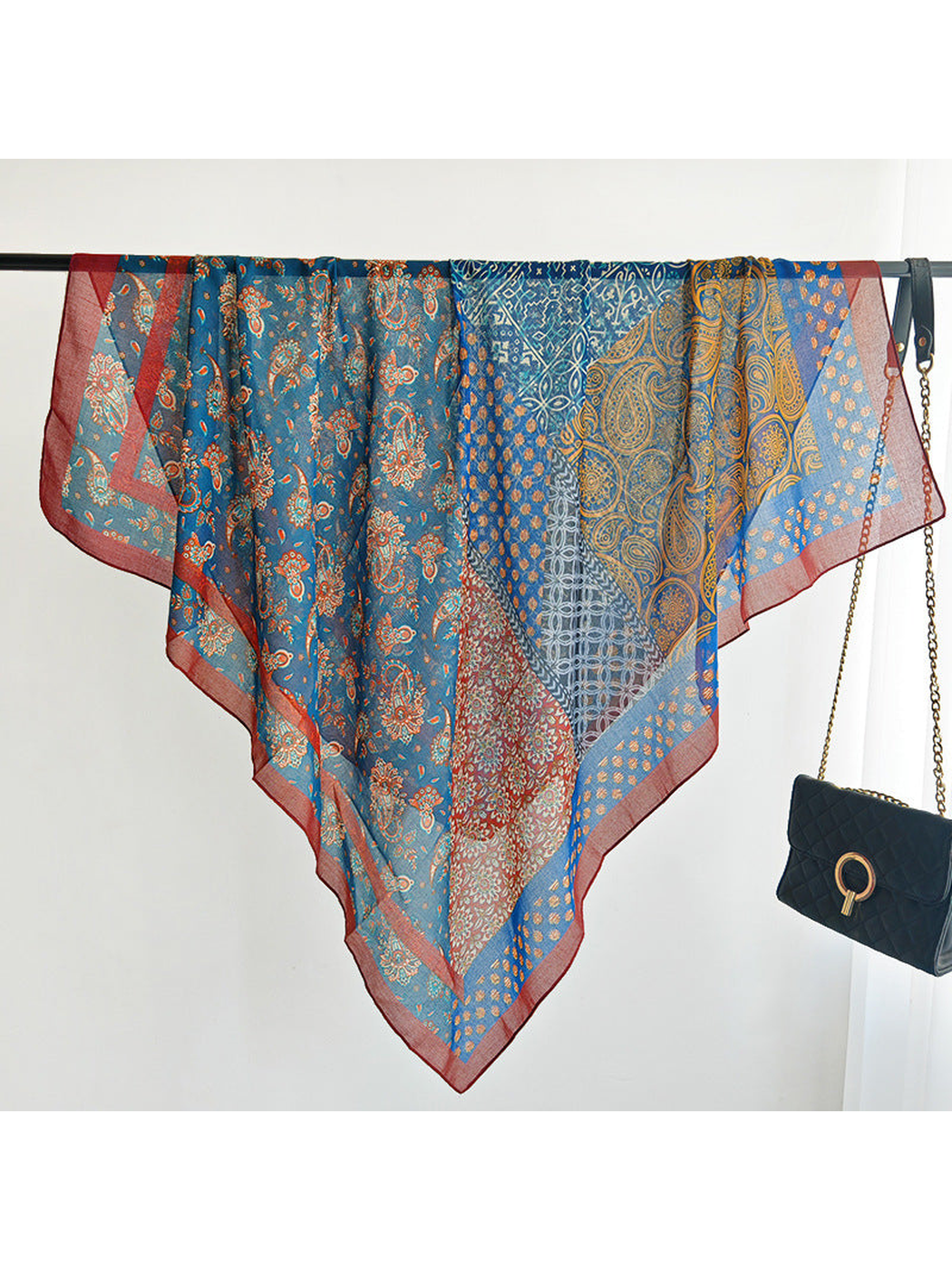 Multicolor square scarf draped over a rail to display its patchwork design