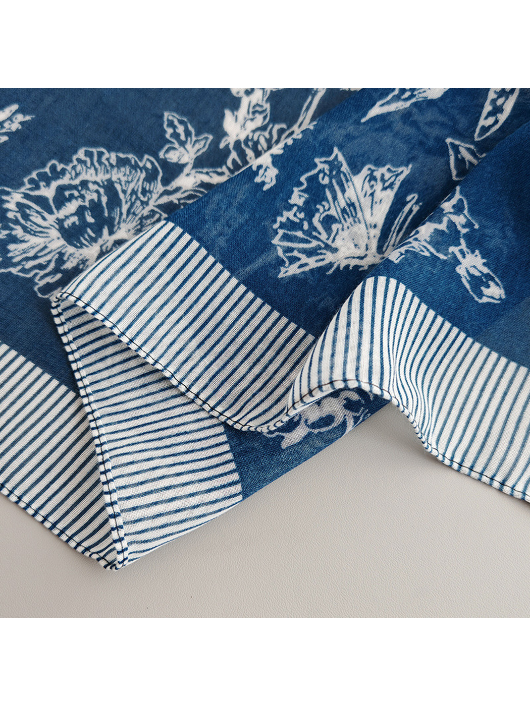 Close-up of the navy blue scarf's stitched striped border and chevron corner