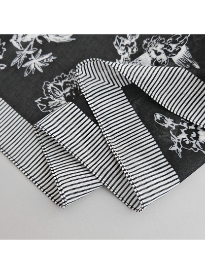 Close-up of the black scarf's stitched striped border and chevron corner