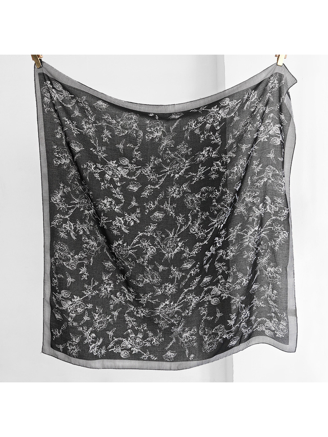 Black square scarf hanging open with white floral, bird and butterfly motifs and a striped border
