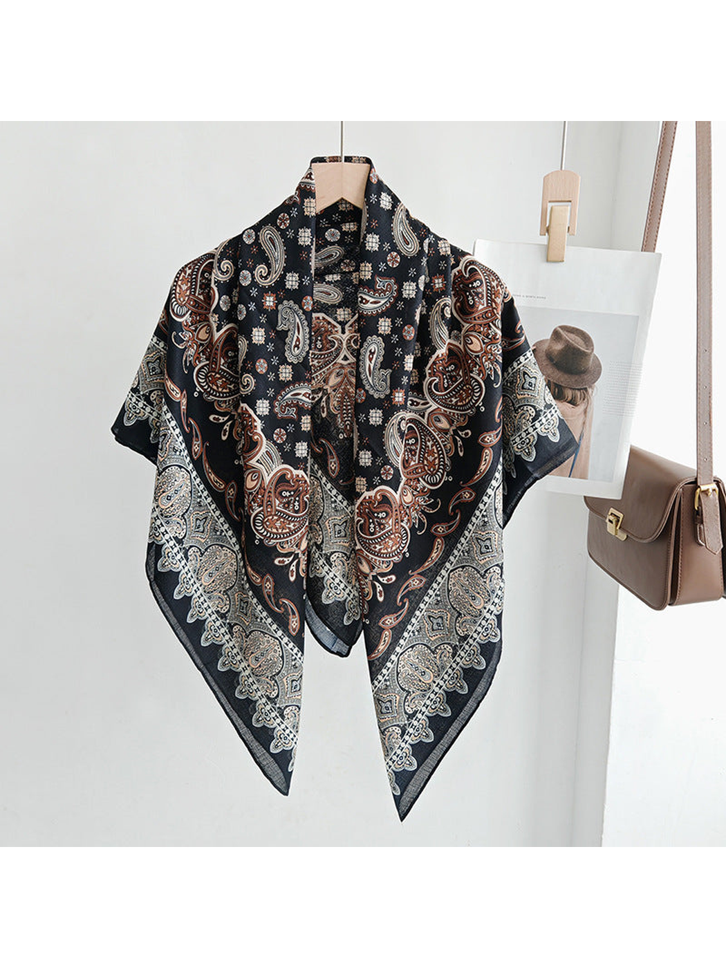 Black paisley square scarf draped loosely on a hanger