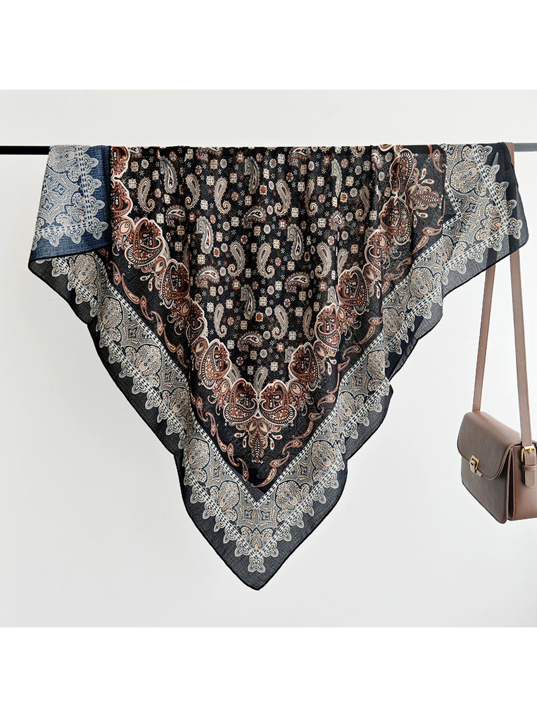 Black paisley square scarf displayed fully draped over a rail