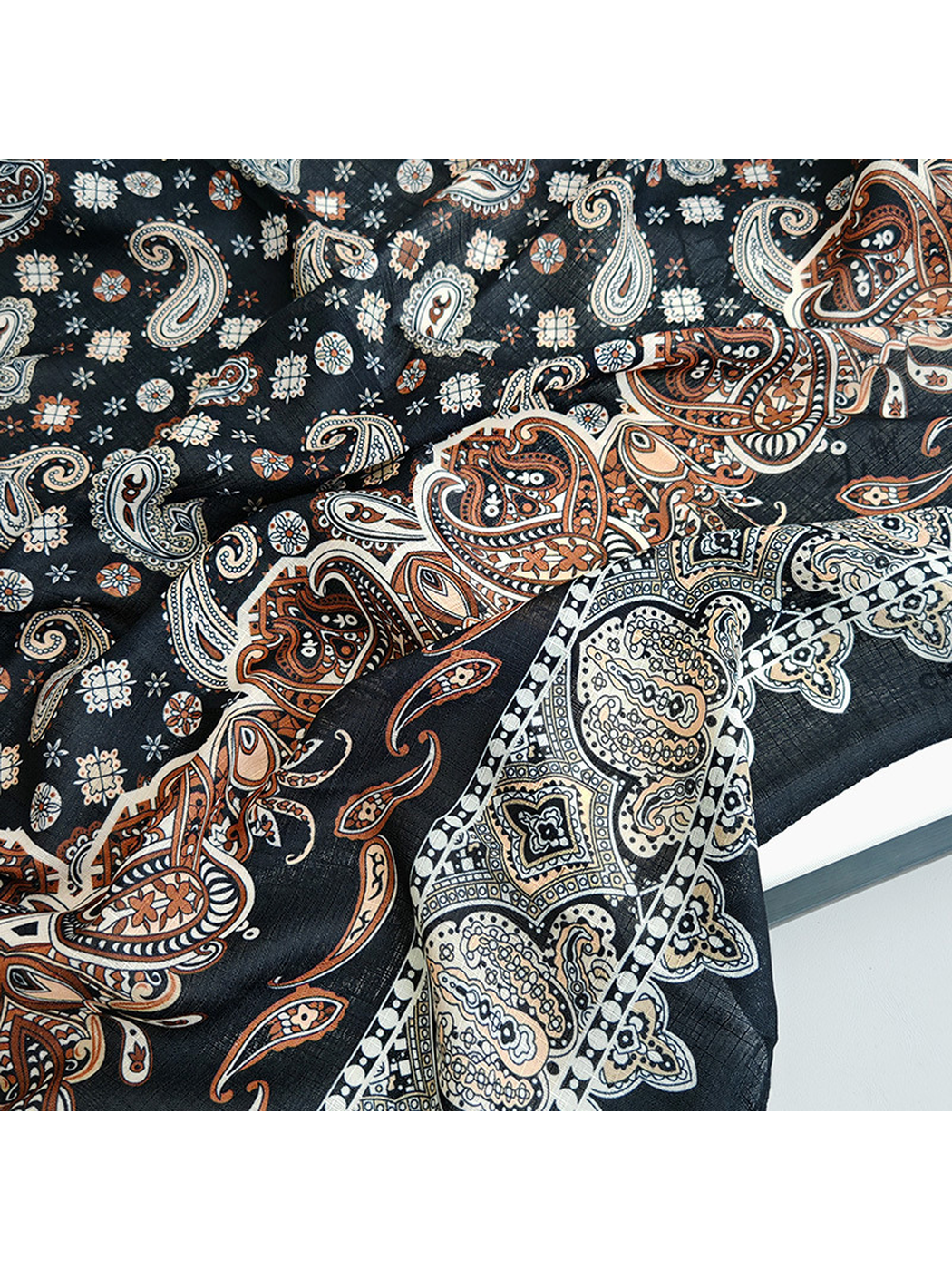Close-up of rust paisley motifs and the pale ornamental scarf border