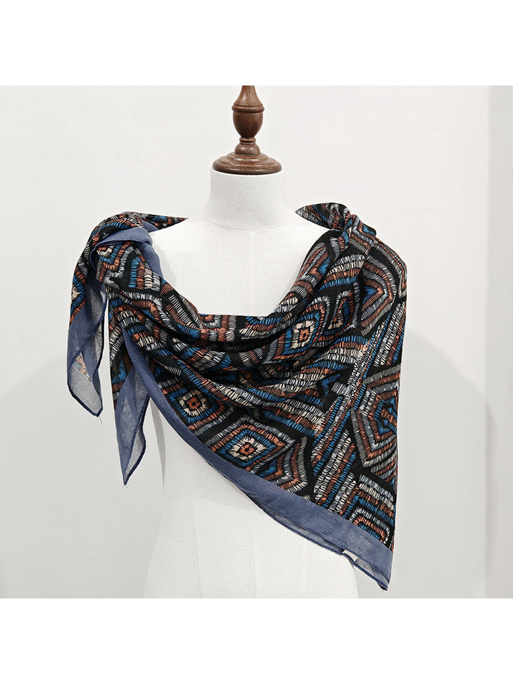 Multicolor geometric square scarf tied over one shoulder on a mannequin