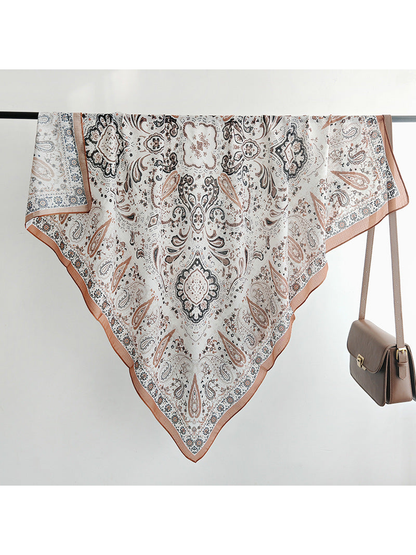 Ivory paisley square scarf draped over a rail