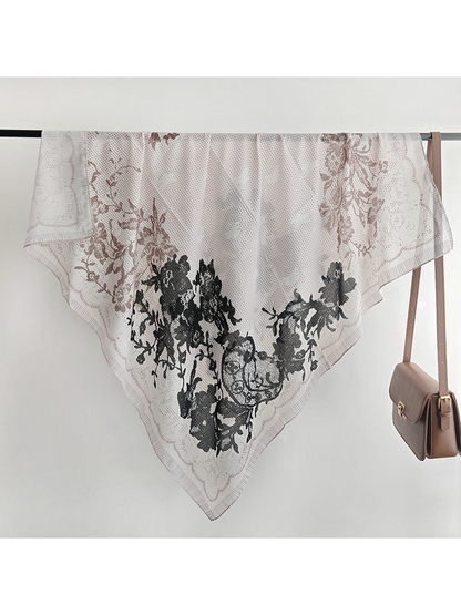 Square floral scarf draped over a display rail beside a handbag