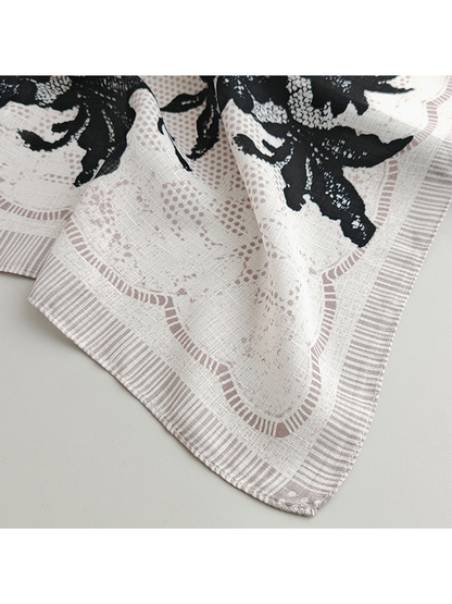 Close-up of a rounded scarf corner with striped edging and black floral print