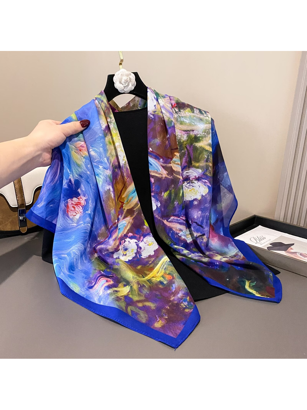 Multicolor square scarf with blue border draped over a hanger