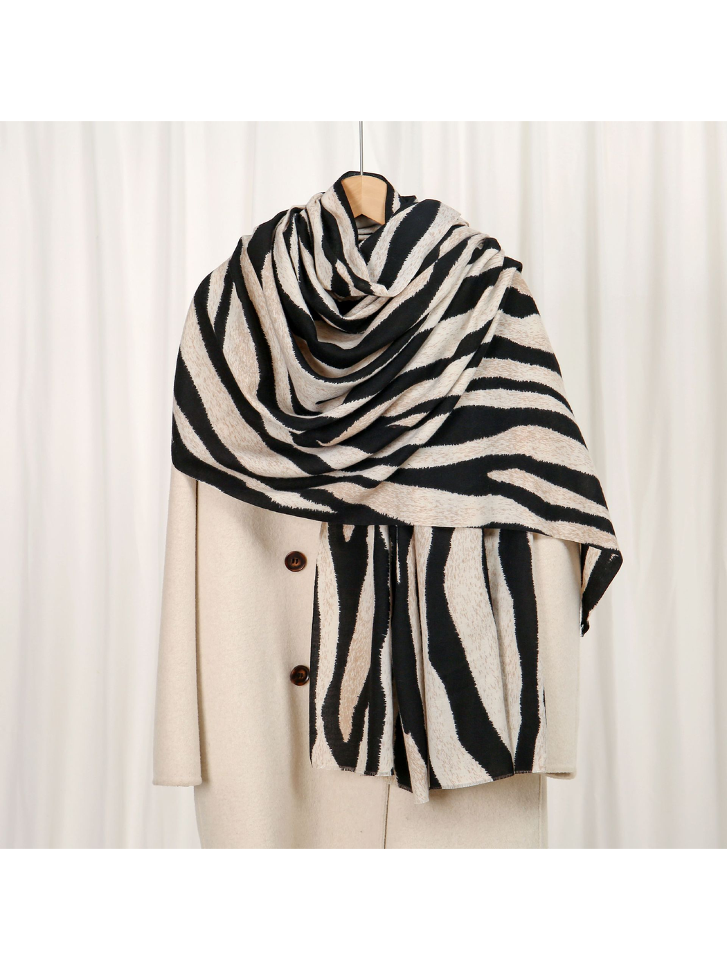 Black and ivory zebra-stripe scarf draped over a cream coat