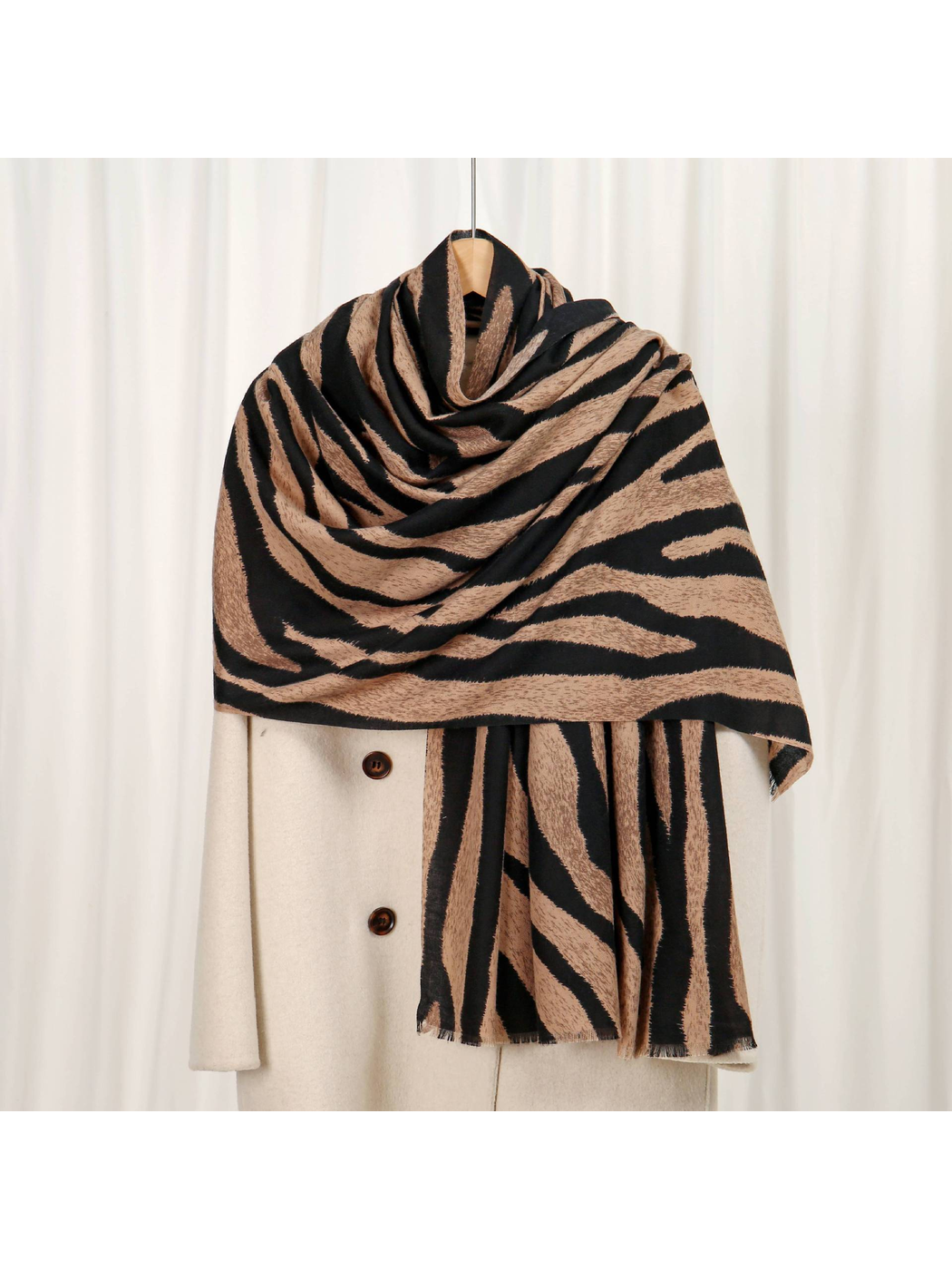 Camel and black zebra-stripe scarf draped over a cream coat