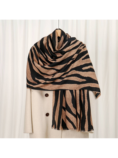 Camel and black zebra-stripe scarf draped over a cream coat