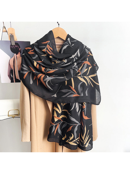 Black leafy branch scarf draped over a neutral coat