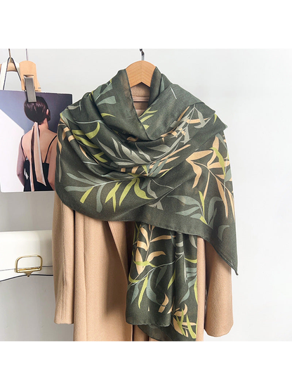 Army green leafy branch scarf draped over a neutral coat