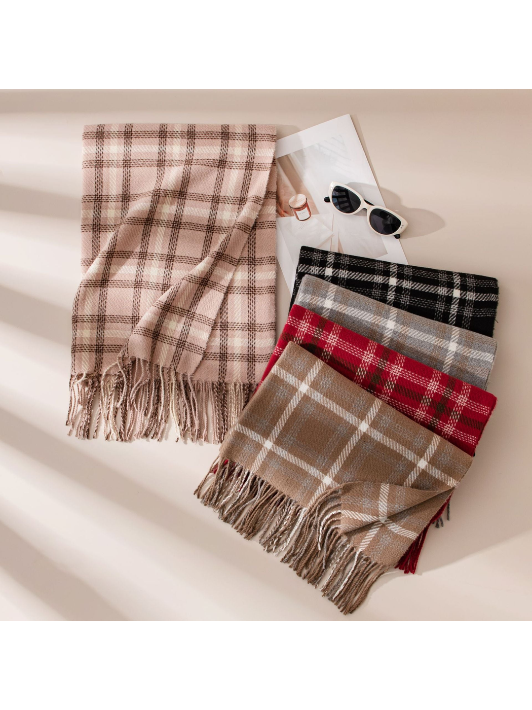 Blush plaid scarf displayed beside folded scarves in assorted colors