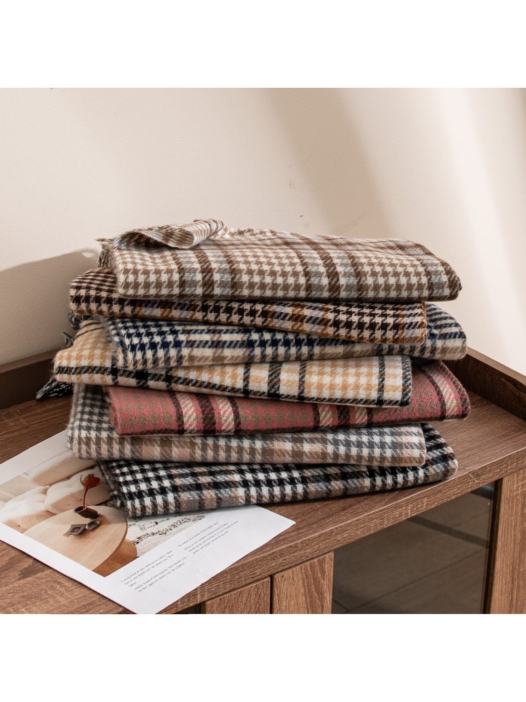 Assorted plaid fringed scarves stacked on a wooden table
