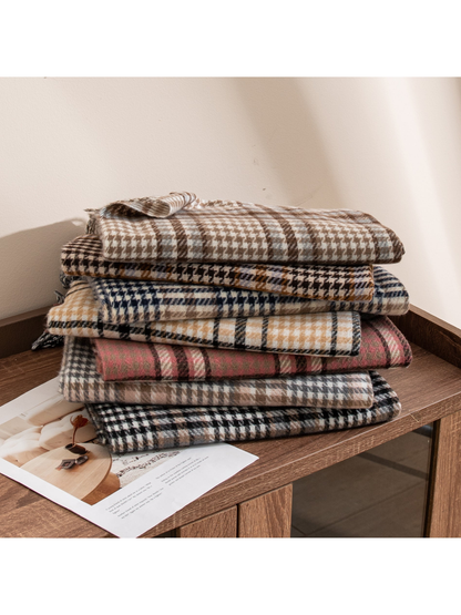 Assorted plaid fringed scarves stacked on a wooden table