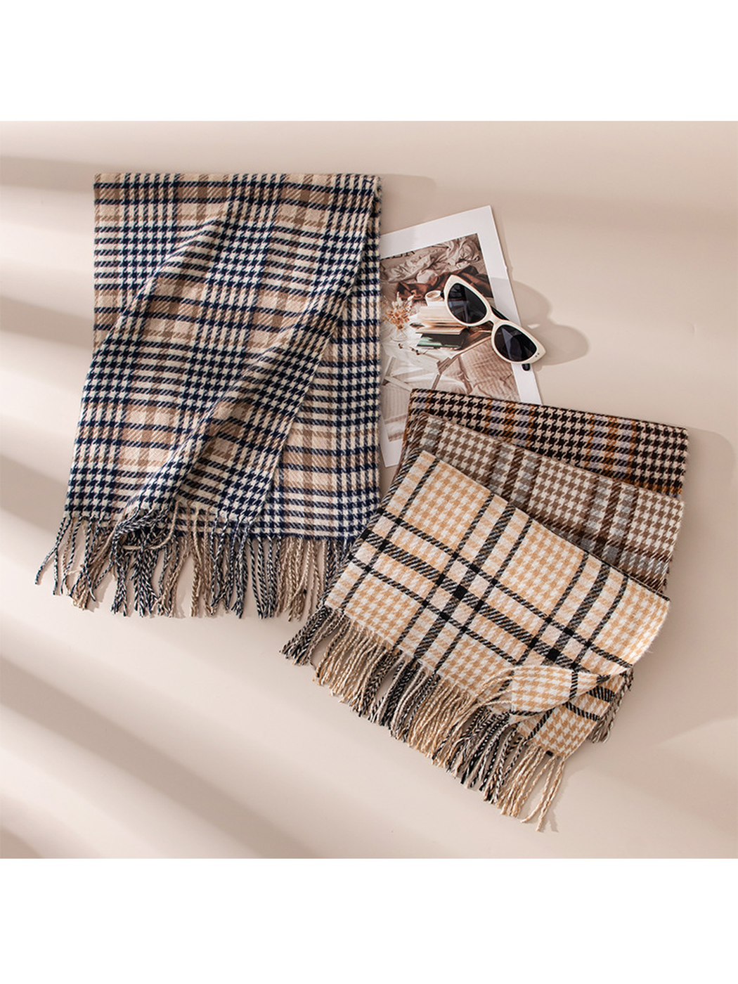 Three plaid fringed scarves arranged with sunglasses in natural light