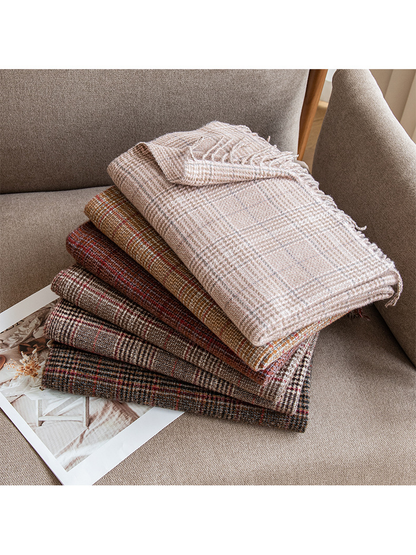 Six folded plaid scarves stacked on an upholstered armchair