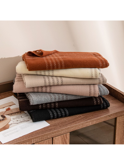Seven plaid scarf colors folded in a stack on a wooden table