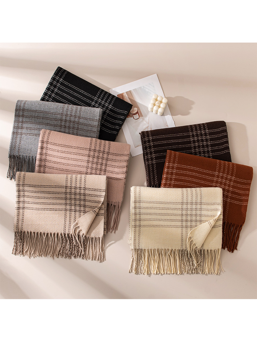 Seven plaid scarf colors arranged in a sunlit flat lay