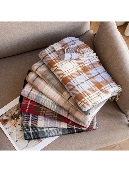 Assorted folded plaid scarves stacked on a neutral chair