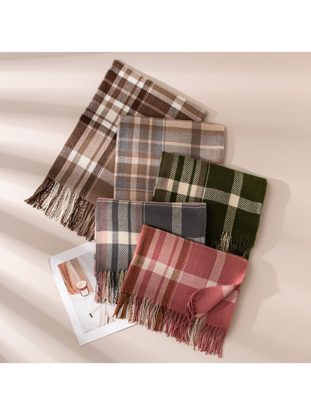 Five plaid fringe scarf colorways arranged in a layered flat lay