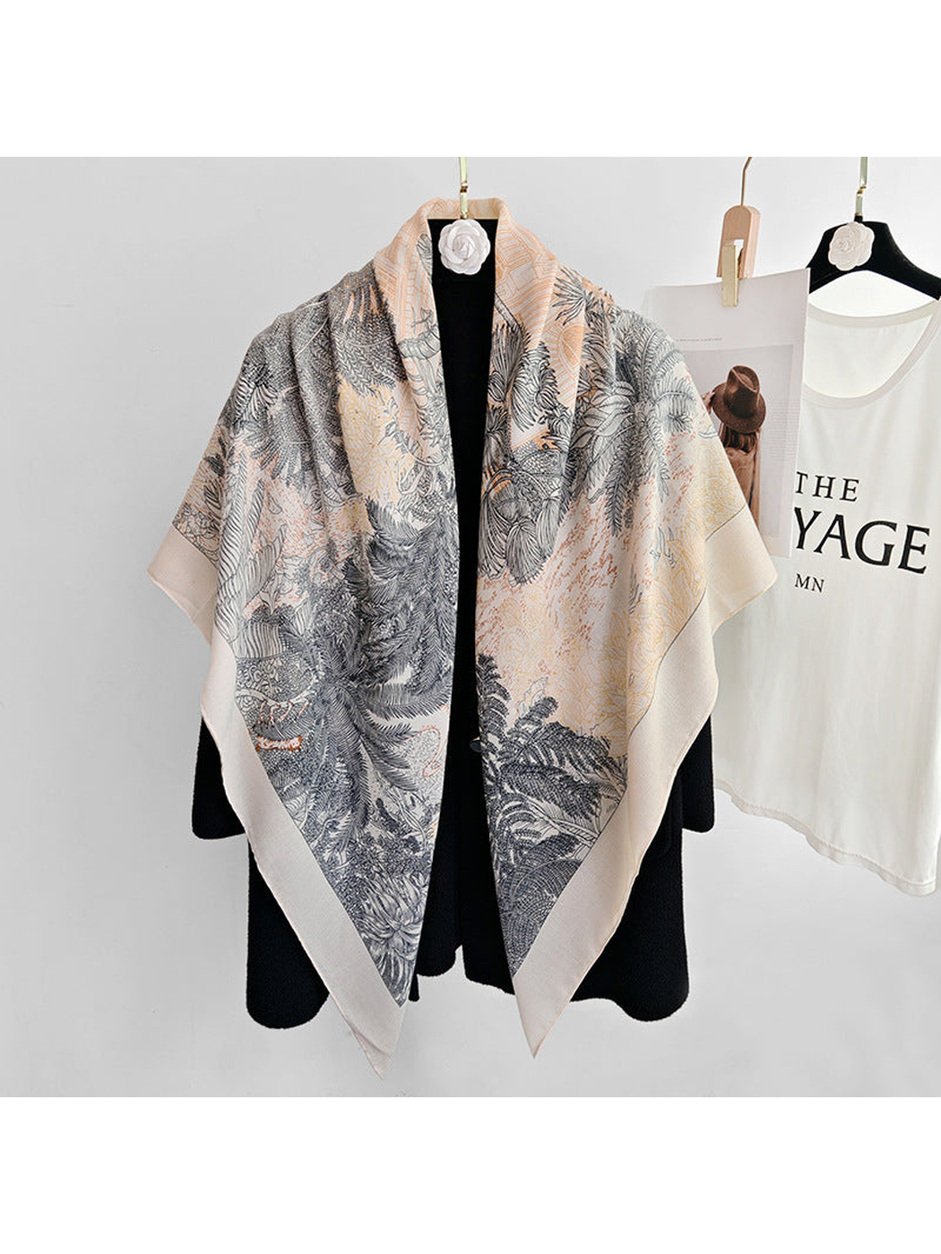 Cream square scarf with botanical and animal print draped over a black coat