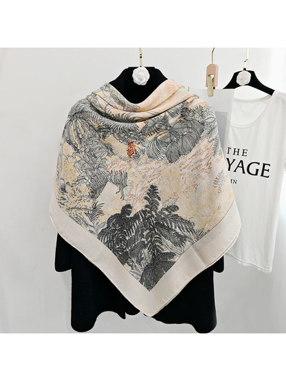 Cream square scarf spread across a black coat to display the botanical print
