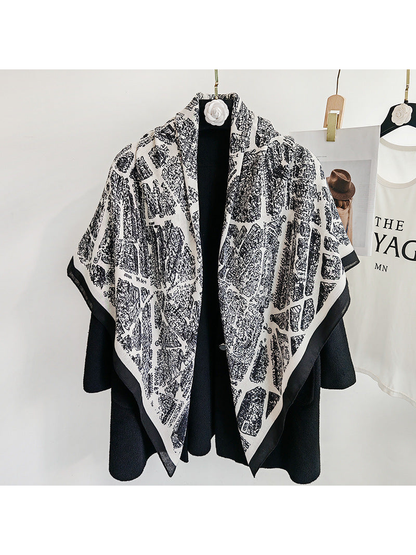 White-base city-map scarf draped loosely over a black coat