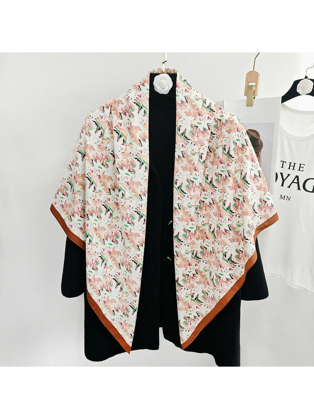 Blush abstract floral square scarf draped over a black coat