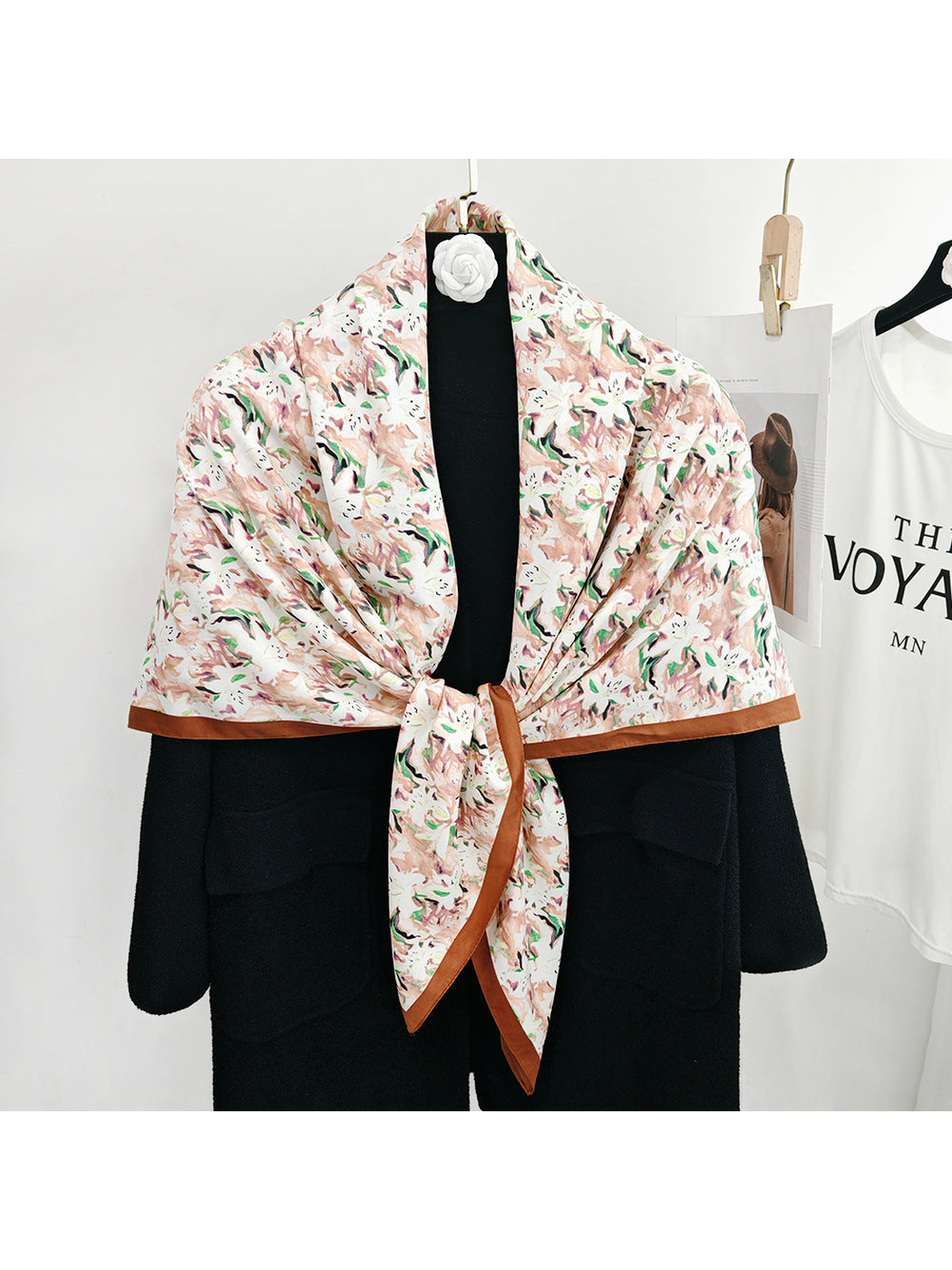 Blush abstract floral square scarf tied over a black coat