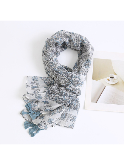 Blue-gray paisley scarf loosely wrapped beside a book and cup print