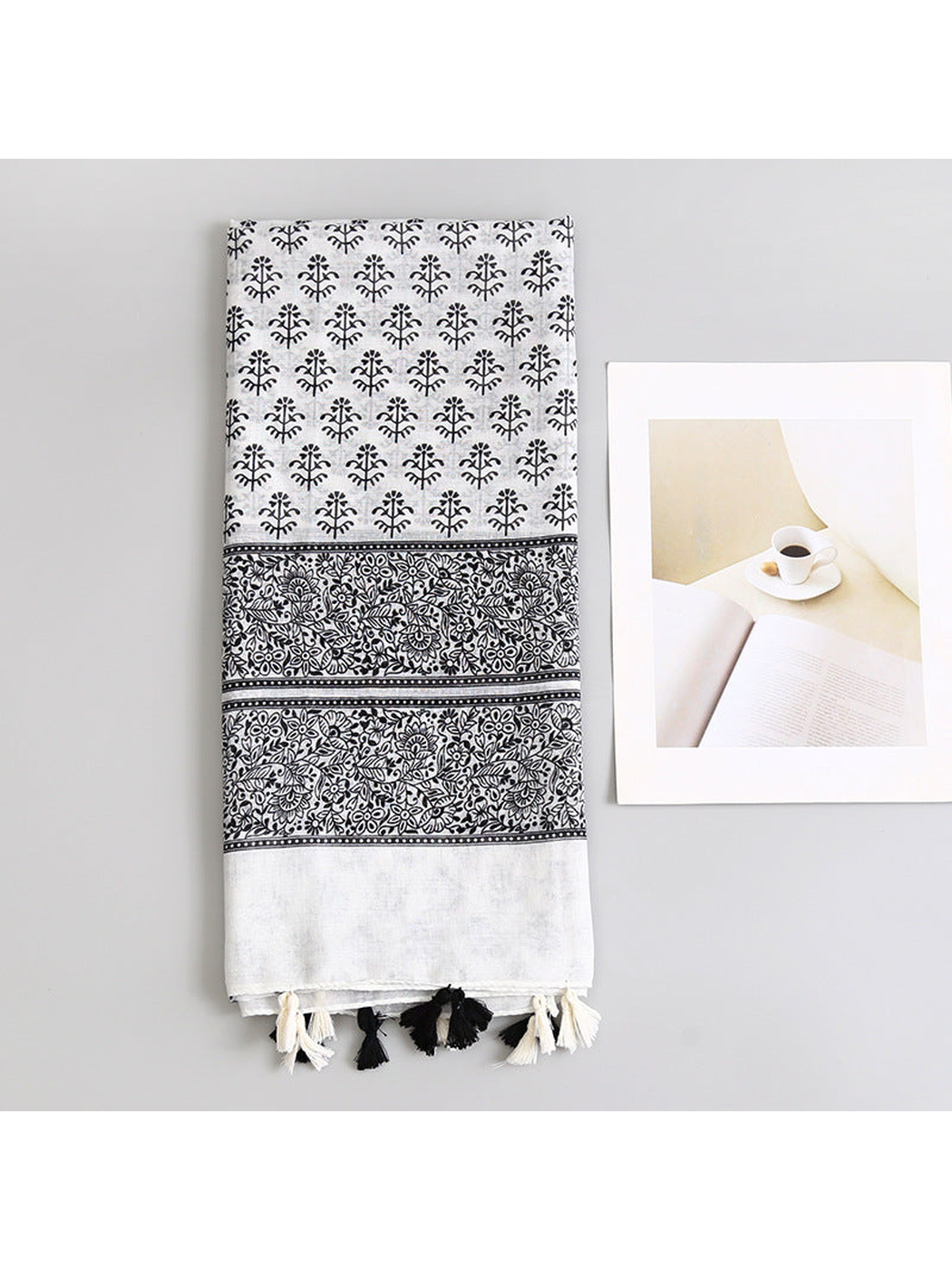 Folded black and white botanical-print scarf with floral border and tassels