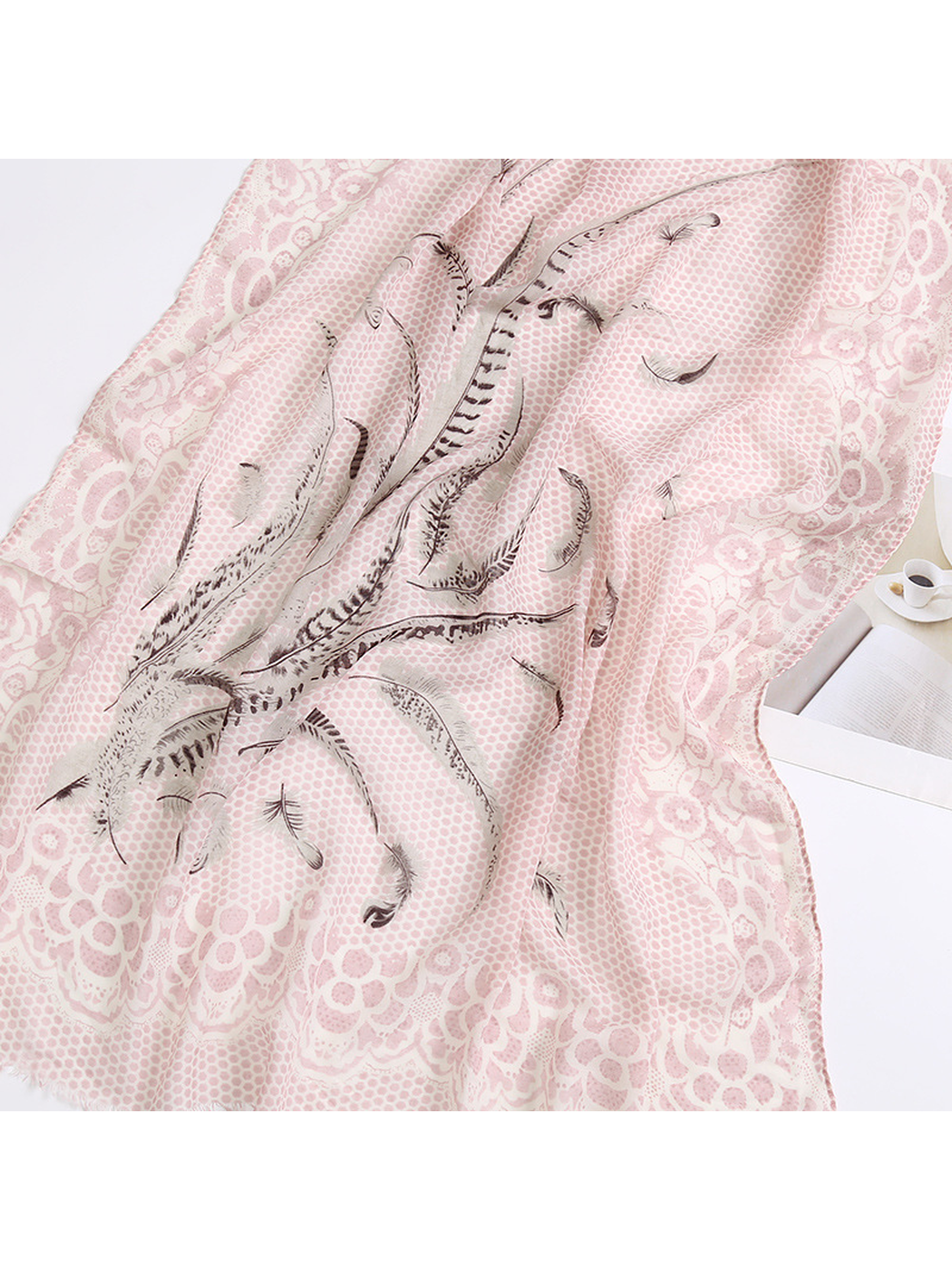 Close-up of the light pink scarf's feather motif and ornate floral border