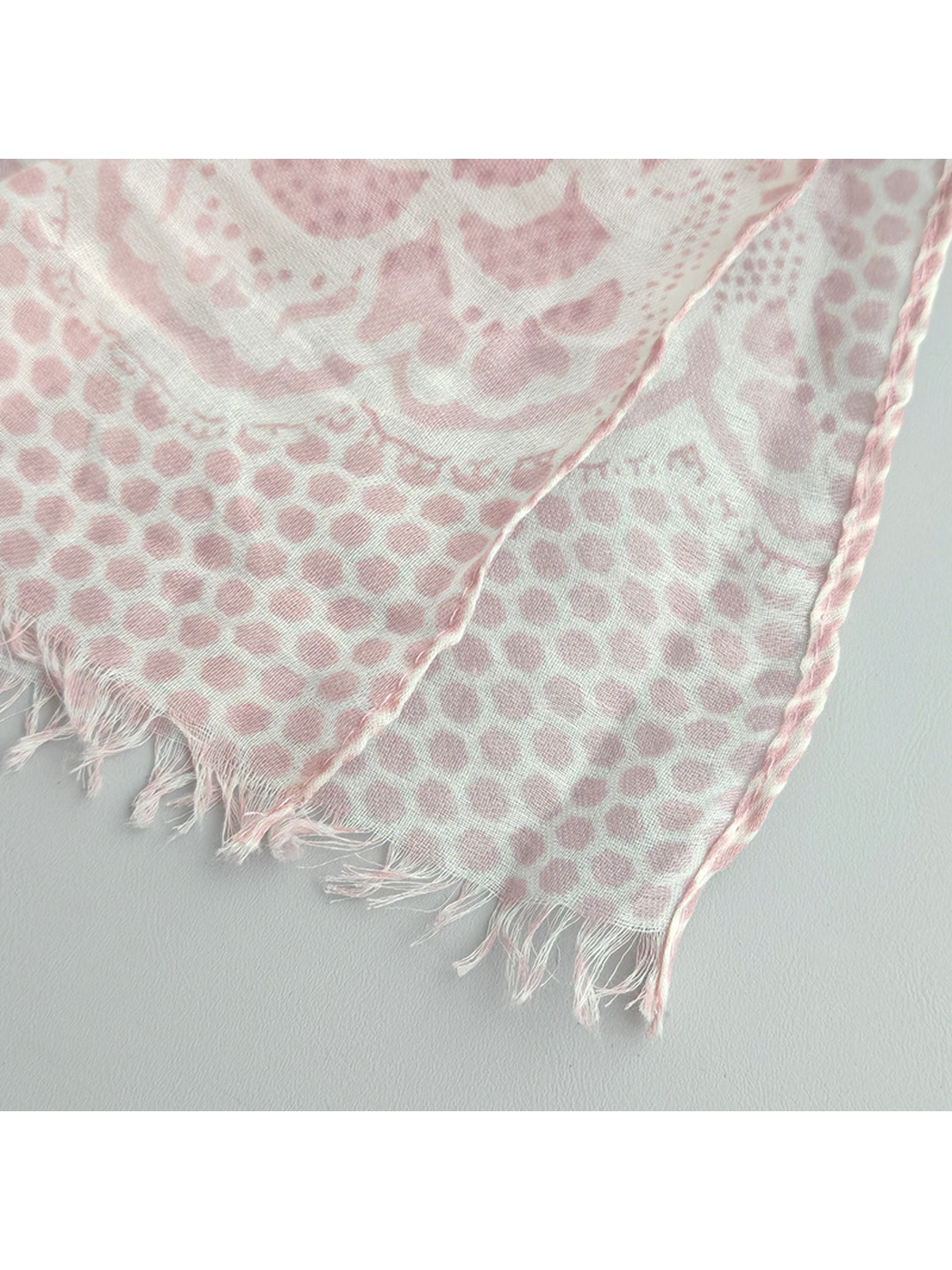 Close-up of the light pink scarf's short fringe and finished side edge
