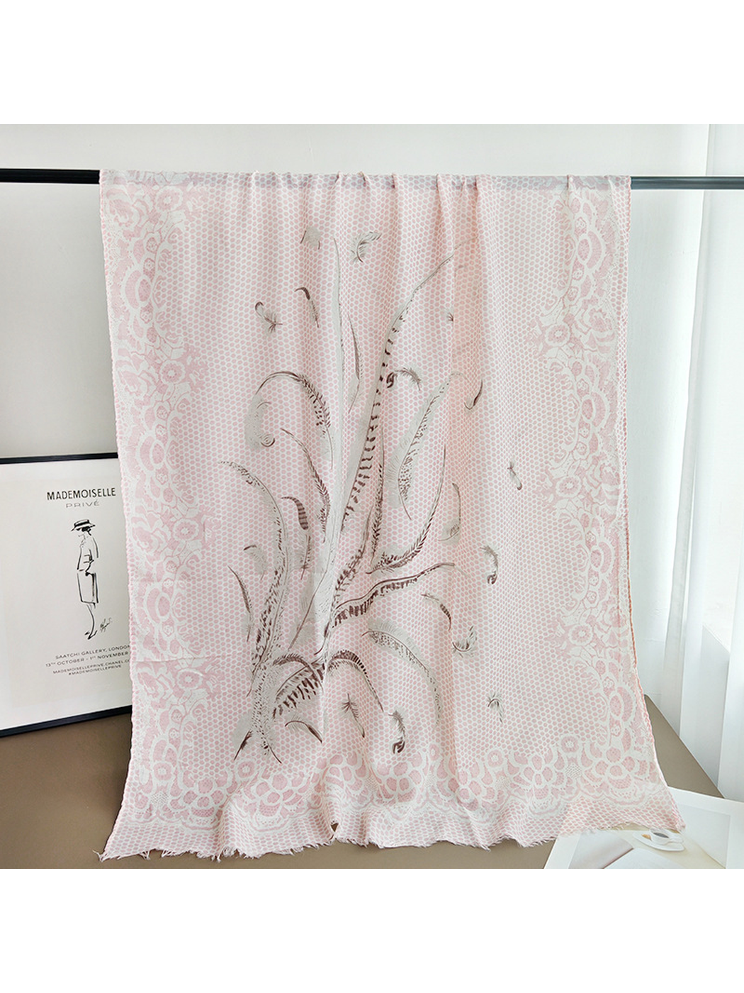 Long light pink patterned scarf draped over a display rail
