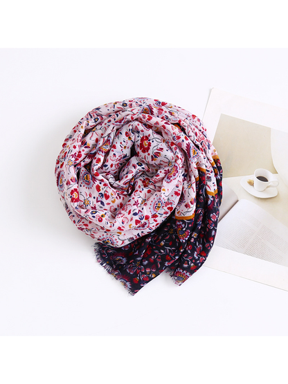 Floral scarf arranged in a loose coil beside a book and cup print